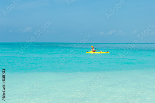 Elderly woman swimming on yellow canoe boat and kayak in turquoise ocean
