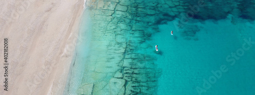 Aerial drone ultra wide photo of couple practice SUP or Stand Up Paddle board in tropical exotic bay with turquoise sea