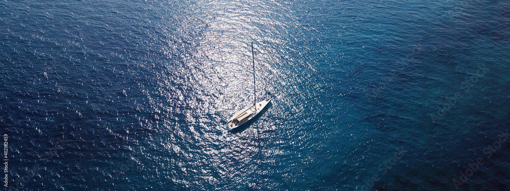 Aerial drone ultra wide photo of sail boat anchored in deep blue Mediterranean Sea