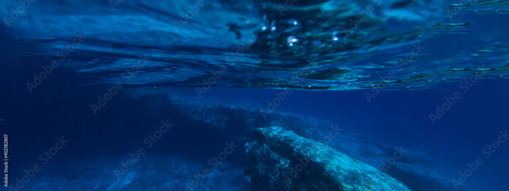 Underwater ultra wide photo of deep blue paradise rocky bay
