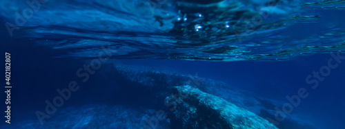 Underwater ultra wide photo of deep blue paradise rocky bay