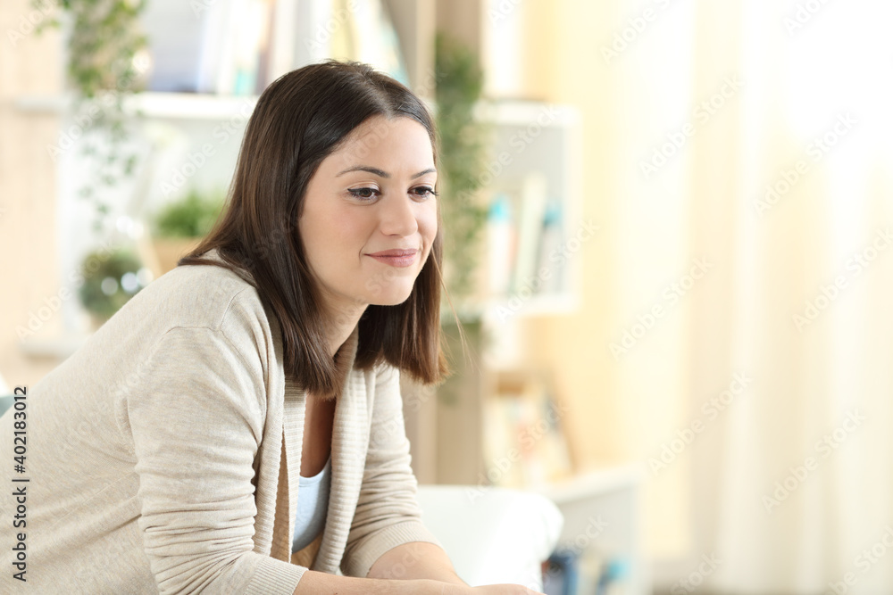 Pensive woman sitting on a sofa at home Pensive woman sitting on a sofa at home