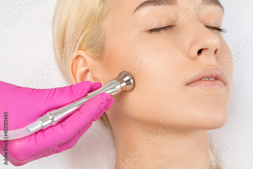 Cosmetologist makes procedure microdermabrasion on the face against acne and blackheads near the eyes. Women's cosmetology in the beauty salon.