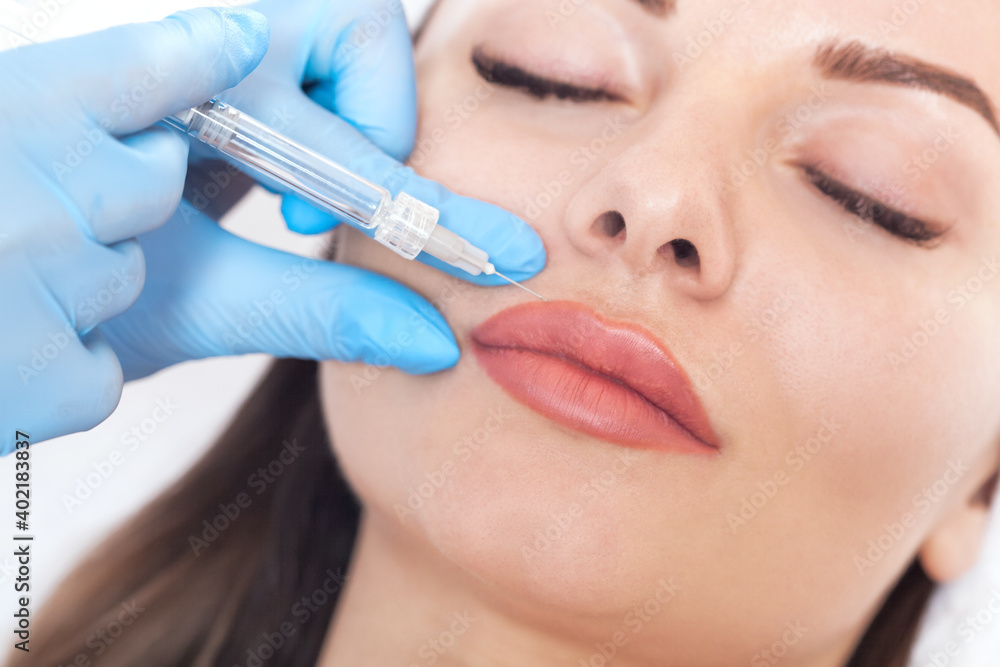 Cosmetologist does injections for lips augmentation and anti wrinkle in the nasolabial folds of a beautiful woman. Women's cosmetology in the beauty salon. Cosmetologist does injections for lips augmentation and anti wrinkle in the nasolabial folds of a beautiful woman. Women's cosmetology in the beauty salon.