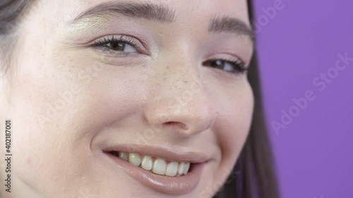 Wallpaper Mural Female model gently stroking hair behind ear while smiling, purple background Torontodigital.ca