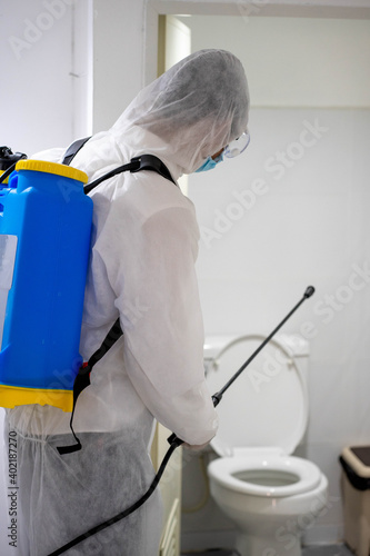 health care worker in white jumpsuit and protective face mask using spraying machine to disinfect virus pandemic. Health care and midicine concept. New normal social distancing concept.
