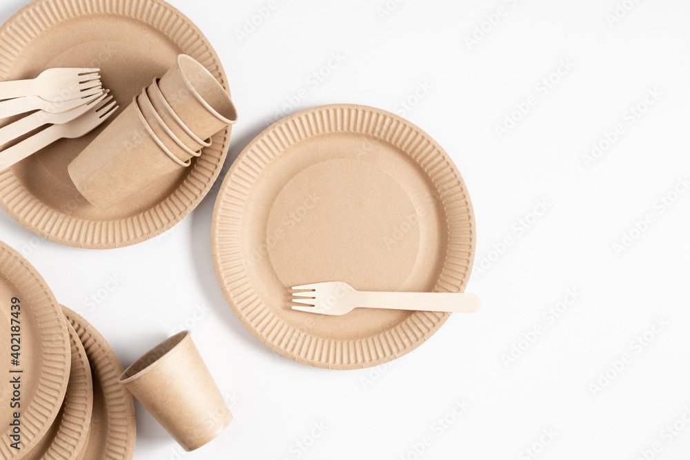 Eco friendly disposable tableware. Wooden forks and paper cups with plates on white background. Eco waste. Flat lay, top view, copy space Eco friendly disposable tableware. Wooden forks and paper cups with plates on white background. Eco waste. Flat lay, top view, copy space