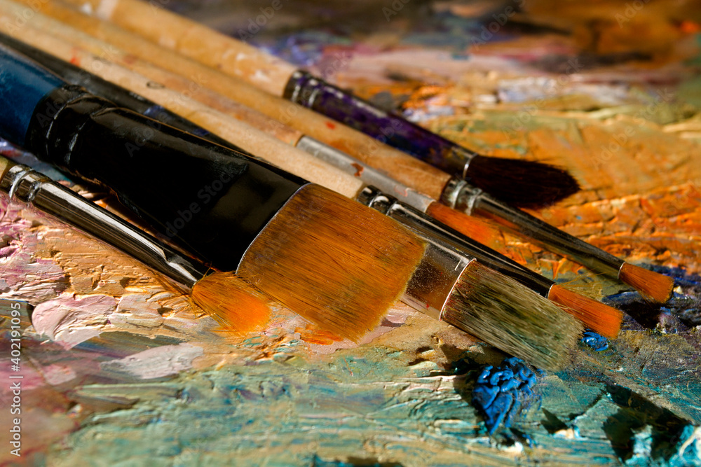 Palette, brushes, selective focus in the foreground. Rough strokes of paint. Abstract. Art. Background. Close-up.