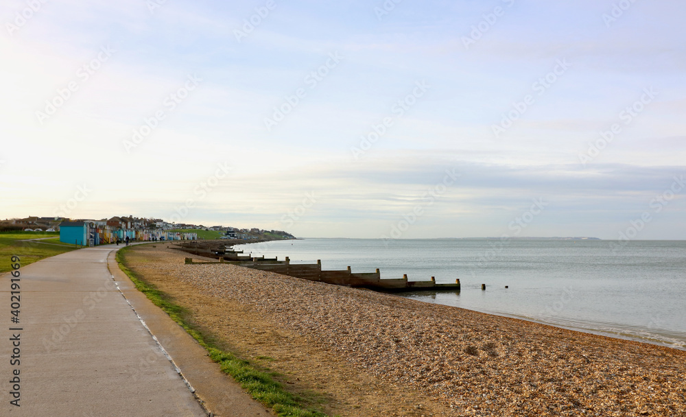 Stony beach with breakwater and beach huts in the distance