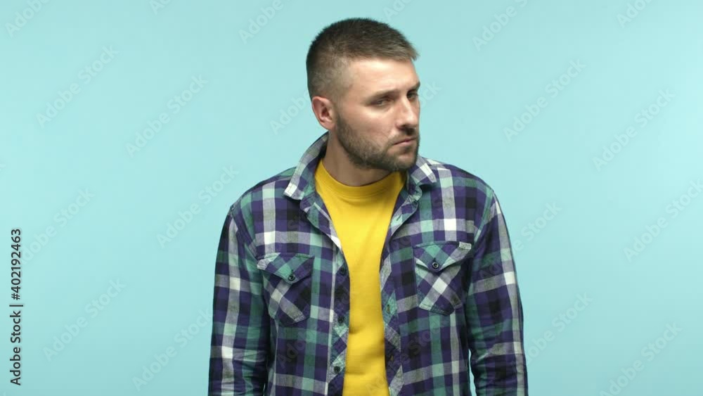 Slow motion of confused adult man looking around, turn head left and right and then pointing at himself surprised, being chosen, standing over blue background