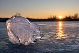 Clear ice close-up sparkling on frozen lake in sunset