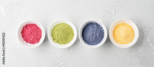 Bowls of multicolored matcha tea powder on a concrete background. Top view.