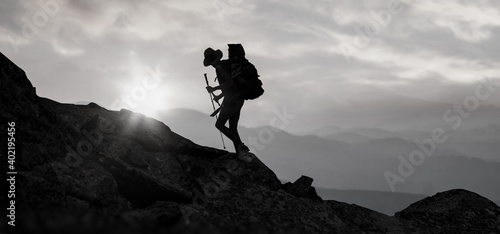 a silhouette Climber with hiking backpack go to the mountain at sunset .