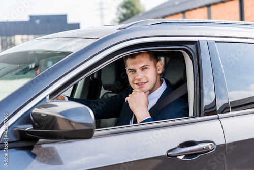 Young businessman smiling at camera in auto on blurred foreground. © LIGHTFIELD STUDIOS