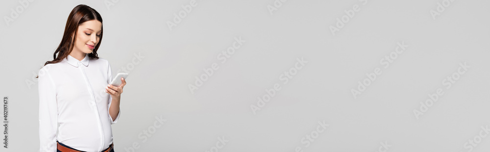 young pregnant businesswoman with smartphone isolated on grey, banner young pregnant businesswoman with smartphone isolated on grey, banner