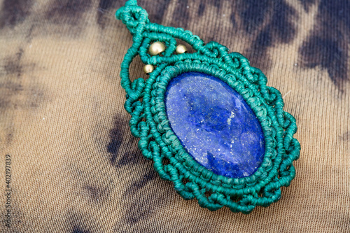 Lapis lazuli gemstone macrame pendant on natural background