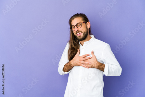 Young man with long hair look has friendly expression, pressing palm to chest. Love concept.