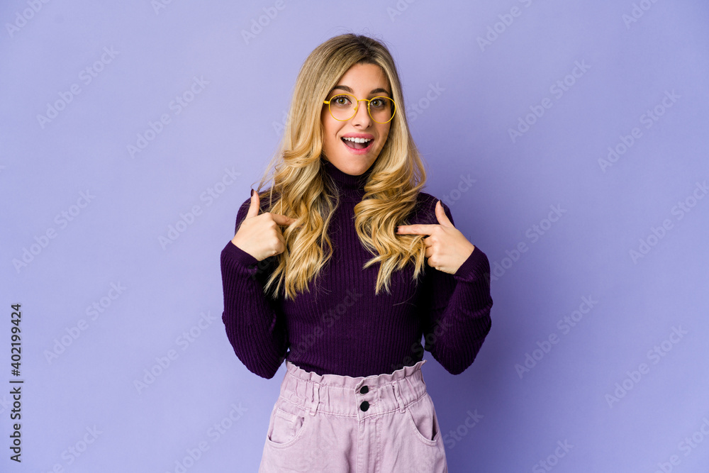 Fototapeta premium Young caucasian blonde woman surprised pointing with finger, smiling broadly.