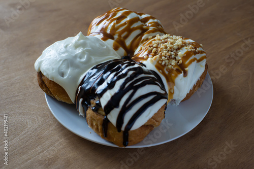 Bakery products. Cinnabon buns watered with different toppings. Buns on a wooden table. Pastries decorated with karmel and chocolate. photo