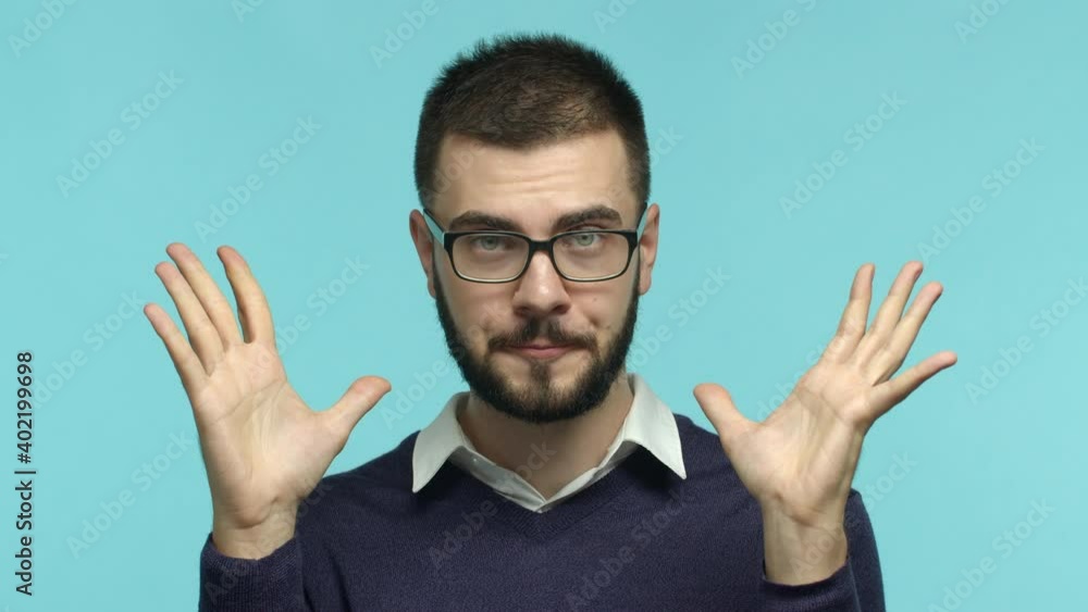 Slow motion of tensed and tired male employee in glasses showing explosion gesture, making head blow sign and saying boom, looking exhausted, blue background Slow motion of tensed and tired male employee in glasses showing explosion gesture, making head blow sign and saying boom, looking exhausted, blue background