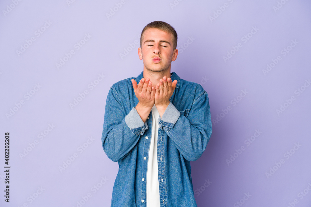 Young caucasian handsome man folding lips and holding palms to send air kiss. Young caucasian handsome man folding lips and holding palms to send air kiss.