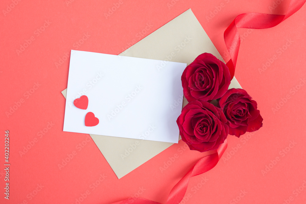 Top view of empty white paper for text, red roses and hearts on the red surface Top view of empty white paper for text, red roses and hearts on the red surface