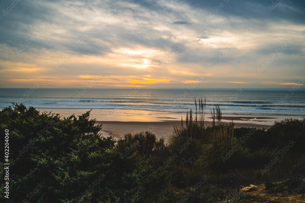 Obraz premium Atardecer en la playa de invierno nubes arena reflejos sur de españa con junco
