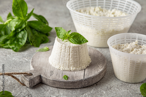 Homemade whey ricotta cheese or cottage cheese with basil ready to eat. Vegetarian healthy, nutritious diet food on a light background photo