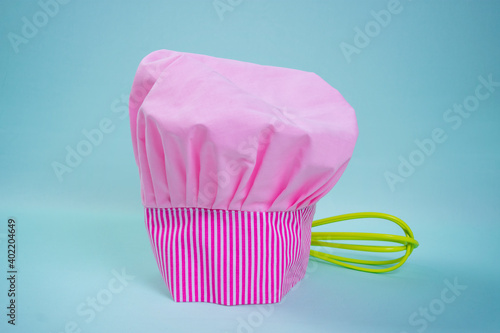 pink chef hat with a whisk on blue background