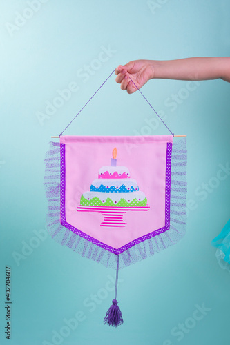 One hand holds a pink banner with cake image