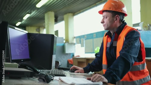 Worker in control room. Heavy industry engineer stand in manufacturing factory, use digital computer. Construction of oil, gas, fuels transport pipeline. Back view sparks flying. Over shoulder shot