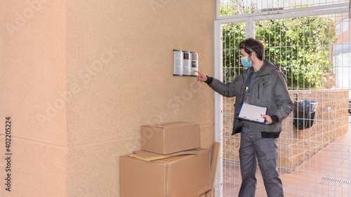 Messenger with mask delivers packages to the doorway next to the doorkeeper