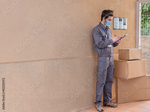 Messenger with mask delivers packages to the doorway next to the doorkeeper