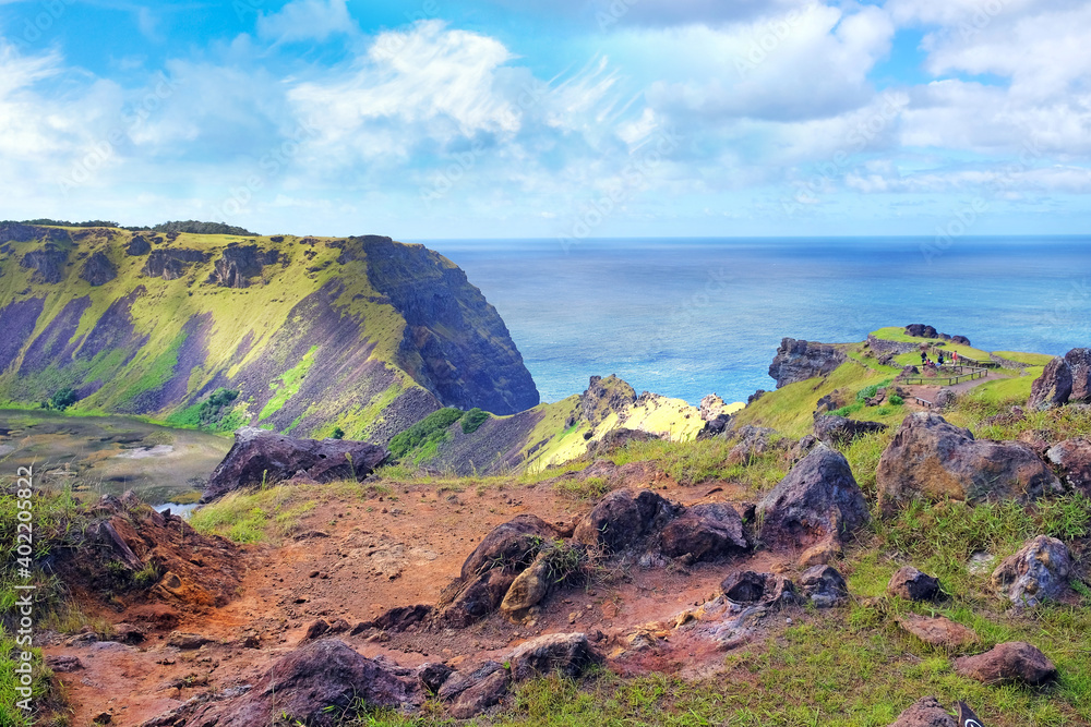 View of the slopes of the Rano Kau volcano, on Easter Island, covered by green vegetation and the Pacific ocean against a blue clear sky.
