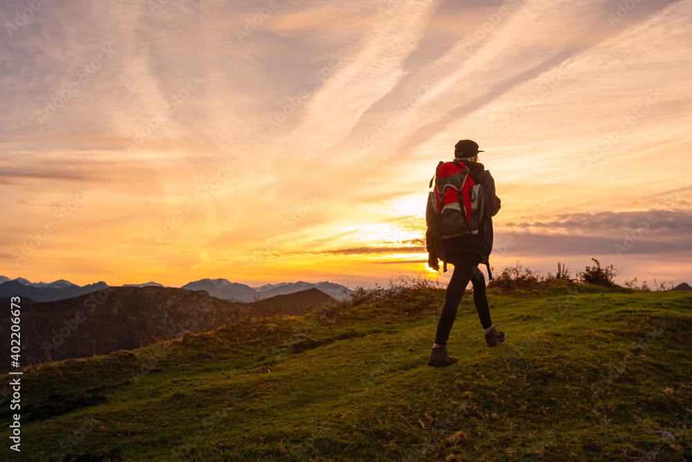 Traveler woman with backpack enjoying a day of mountaineering alone with a beautiful sunset. sports and mountain