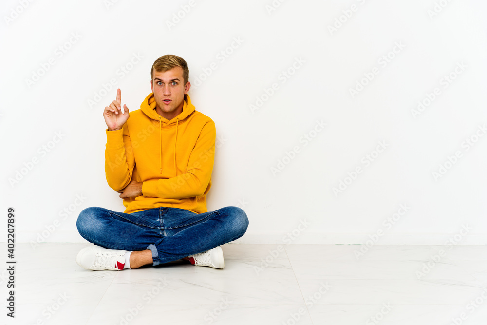 Young caucasian man sitting on the floor having some great idea, concept of creativity.