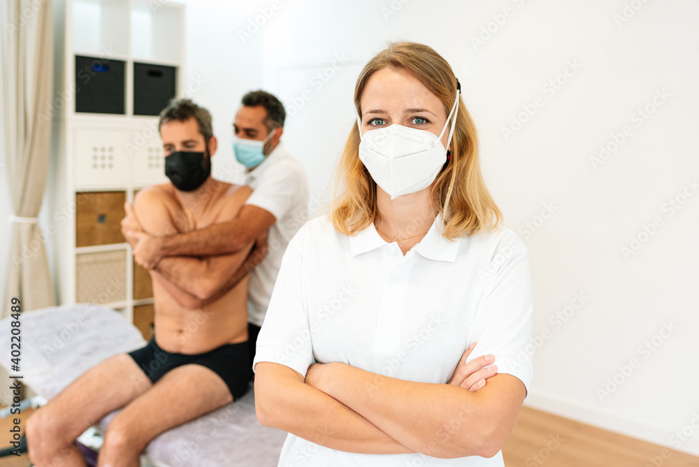 Portrait of a female physiotherapist with a mask and crossed arms in the rehabilitation clinic. Space for text Portrait of a female physiotherapist with a mask and crossed arms in the rehabilitation clinic. Space for text
