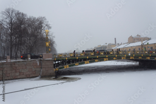 View of the Panteleimonovsky bridge over the snow-covered Fontanka river in St. Petersburg on a snowy and traditionally gloomy day in December. Winter in Russia photo