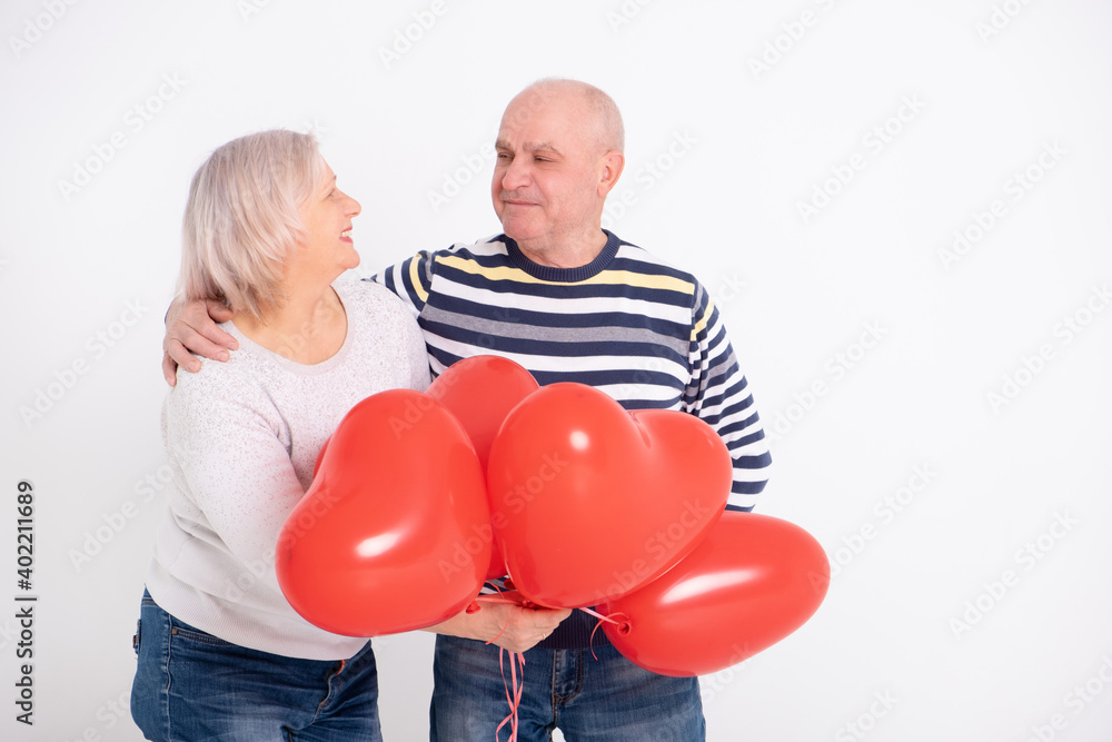 senior couple hugging holding red heart balloons. senior couple hugging holding red heart balloons.