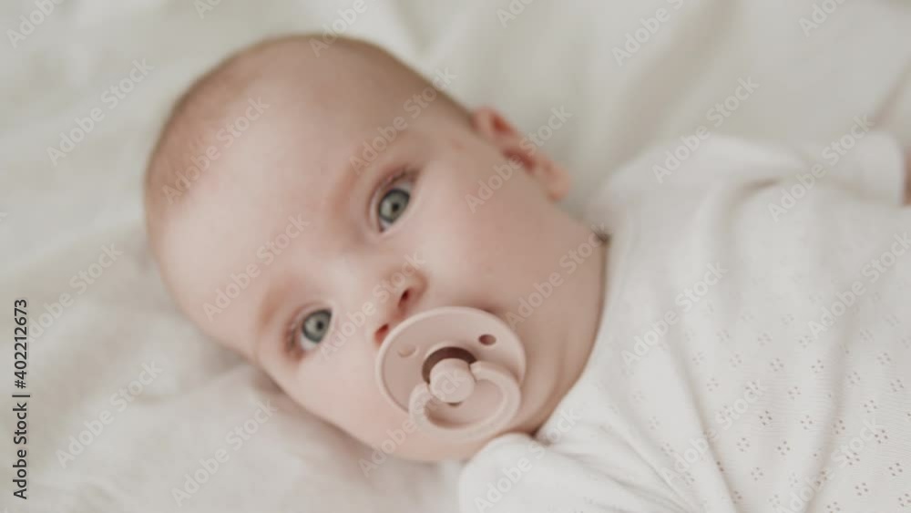 Surprised little baby with nipple in mouth looking at camera with big green eyes Surprised little baby with nipple in mouth looking at camera with big green eyes