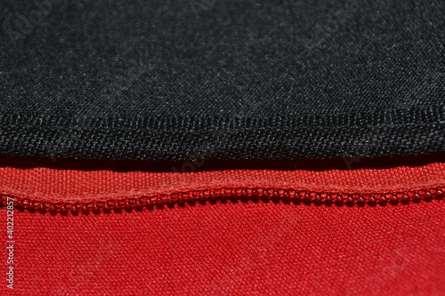 close-up view of a zipper sewn to red and black neoprene fabrics