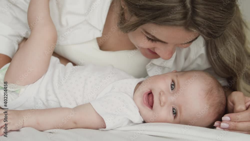 Young woman kissing adorable baby, playing with newborn, parent affection, love Young woman kissing adorable baby, playing with newborn, parent affection, love