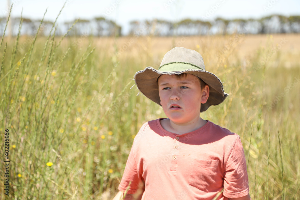 Country boy standing in field full of long grass. Summer in Australia