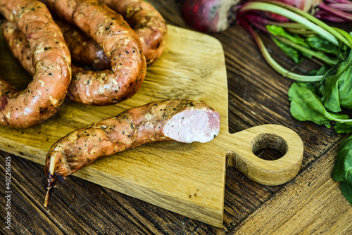 Sausage served on an oak board among vegetables from the home garden.