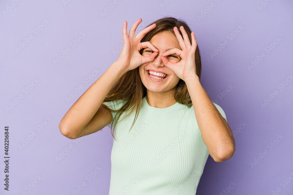 Young skinny caucasian girl teenager on purple background showing okay sign over eyes Young skinny caucasian girl teenager on purple background showing okay sign over eyes