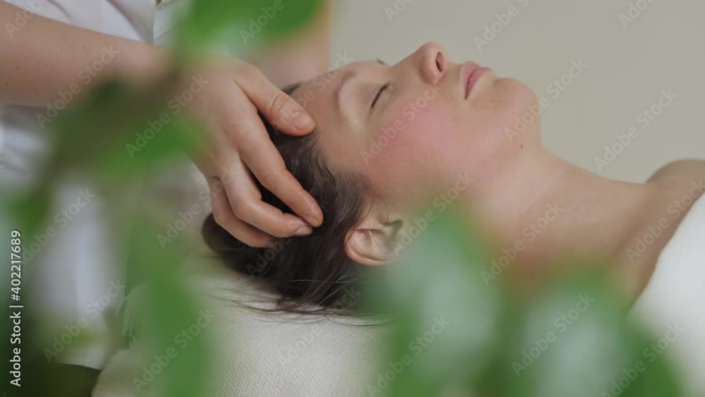 A pretty brunette woman gets a head massage in the bright office of the spa salon. High quality 4k footage A pretty brunette woman gets a head massage in the bright office of the spa salon. High quality 4k footage