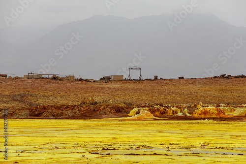 yellow and red stones in a volcanic crater that smoke and boil from the heat, where abandoned sulfur mining buildings remain photo