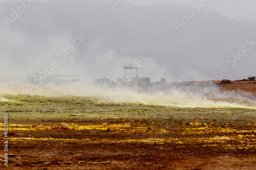 yellow and red stones in a volcanic crater that smoke and boil from the heat  where abandoned sulfur mining buildings remain
