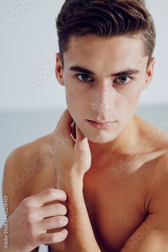 Cute guy touches his neck with his hand portrait of a naked torso