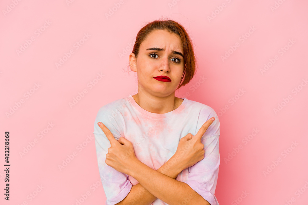 Fototapeta premium Young arab mixed race woman points sideways, is trying to choose between two options.